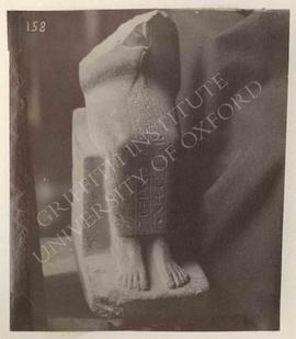 Headless statuette (in cloak) of Reni, grey granite, early Dyn. XVIII, from El-Kab, now in Turin,...